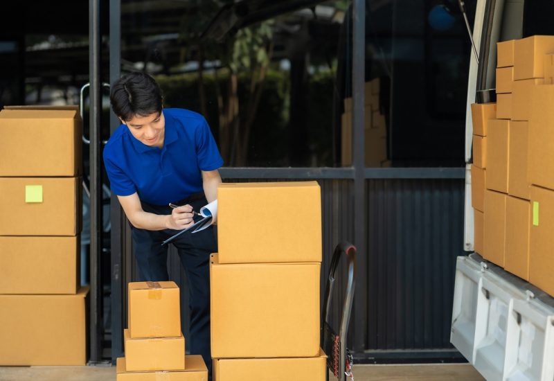 Asian delivery man, delivery men unloading cardboard boxes from truck.